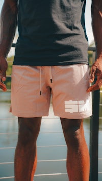 a man wearing pink shorts and a black t - shirt