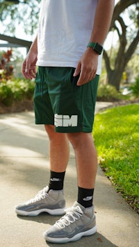 a man wearing green shorts and a white t-shirt